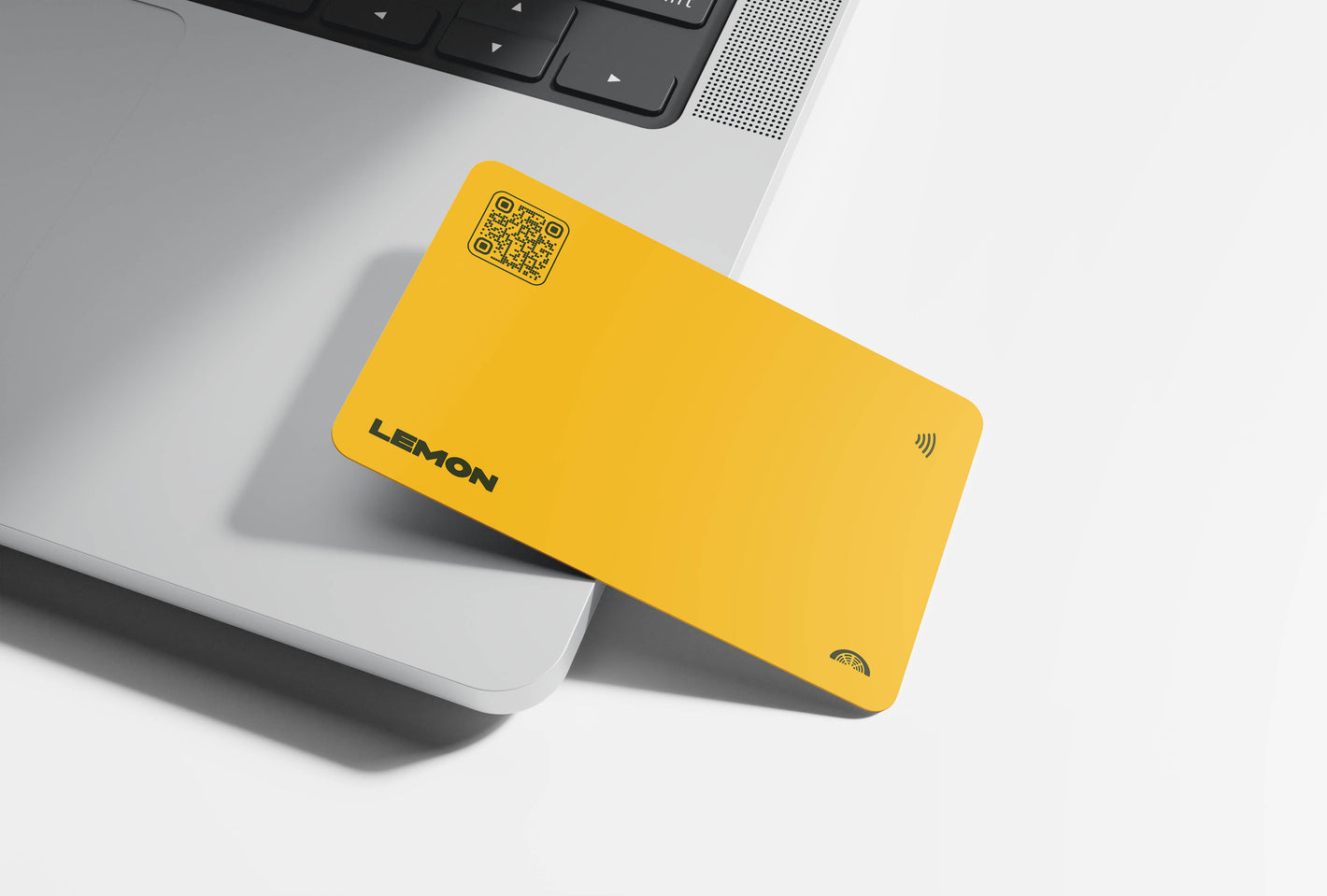 A yellow NFC-enabled business card sitting on top of a laptop.	